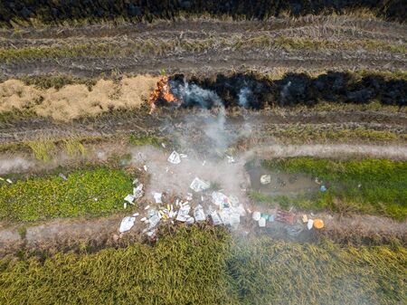 Aerial view open burning at paddy field. The pesticide waste is thrown at side.の写真素材