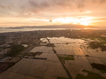 Dramatic sunset over paddy field at Perai. Background is Penang Bridge.の写真素材