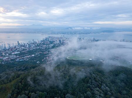 Aerial view green forest in sea cloud morning. Background is Georgetown and Gurney Drive in development.の写真素材