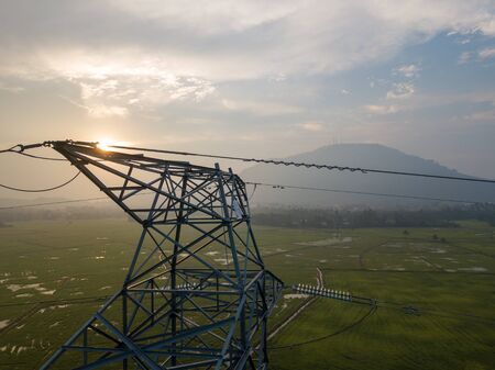Aerial view at top of electric tower in sunrise morning at paddy field. Background is Cherok Tokkun Hill.の写真素材
