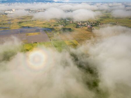 Rainbow halo over cloud. Background is paddy field.の写真素材