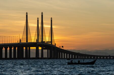 Silhouette fishing boat near Penang Second Bridge during sunrise.の写真素材