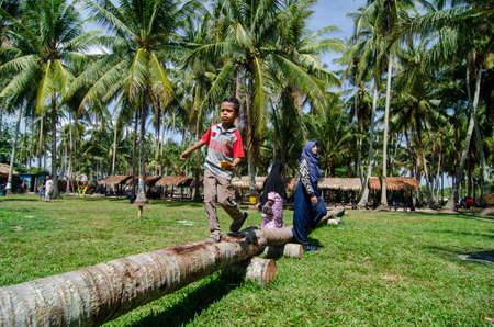 Penaga, Penang/Malaysia - Mar 15 2020: Kids walk on the trunk pf coconut.のeditorial素材
