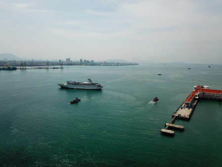 Georgetown, Penang/Malaysia - Mar 17 2020: Drone view tug boat assist cruise ship to departure.のeditorial素材