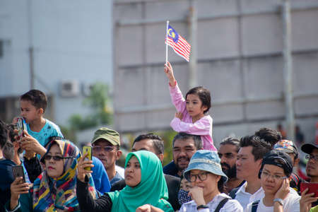Butterworth, Penang/Malaysia - Aug 31 2019: Girl hold Malaysia flag in the crowd.のeditorial素材