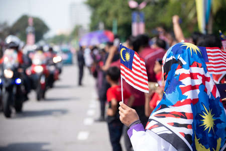 Butterworth, Kuala Lumpur/Malaysia - Aug 31 2019: A muslim girl hold Malaysian tudung and mask wave the Malaysia flag during independence day.のeditorial素材