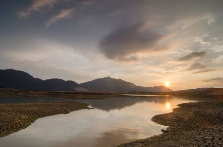 Sunset of Mengkuang Dam, Bukit Mertajam. Dry land and reflection of Tokkun Hill can be seen.の写真素材