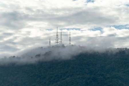 Communication transmitter tower on the hill top in foggy weather.の写真素材
