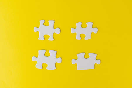 Pieces of white jigsaw puzzle on yellow backgroundの写真素材