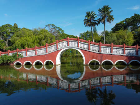 Red Chinese style red traditional bridge near the pond under blus skyの写真素材