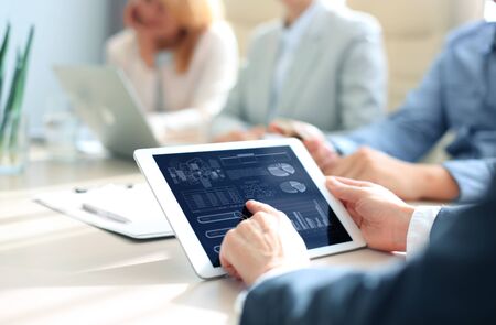 Cropped shot of a group of businesspeople looking at graphs on digital tabletsの写真素材