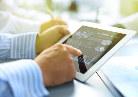 Cropped shot of a group of businesspeople looking at graphs on digital tabletsの写真素材