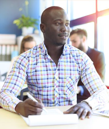 Portrait of smiling African American business man with executives working in backgroundの写真素材