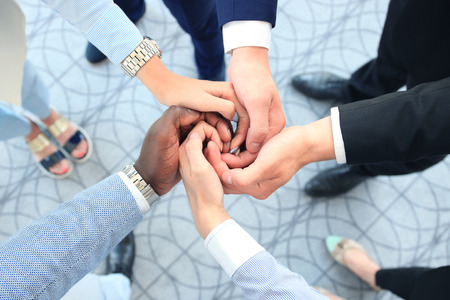 Multiethnic group of young people putting their hands on top of each other. Close up image of young...