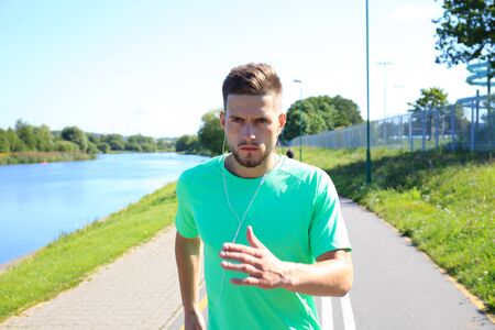 Running sport man. Fit muscular young male runner sprinting at great speed outdoors on road.