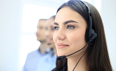 Portrait of call center worker accompanied by her team. Smiling customer support operator at work