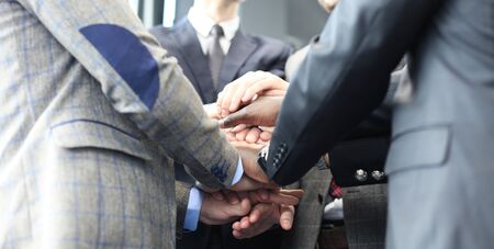 Businessman team in suit touching hands together. Selective focus.