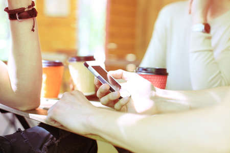 Three cheerful young people meeting and using smartphone with laptop at outdoor cafe.の写真素材