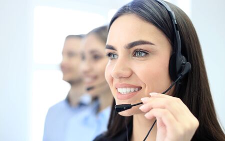 Portrait of call center worker accompanied by her team. Smiling customer support operator at work.