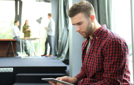 Smiling young man using digital tablet in the office.の写真素材