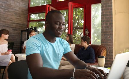 Portrait of a happy African American entrepreneur displaying computer in office.