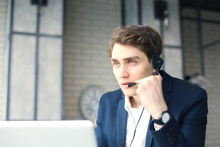 Smiling friendly handsome young male call centre operator.