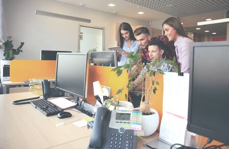 Group of young modern people in smart casual wear having a brainstorm meeting while standing in the...