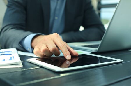 Business person analyzing financial statistics displayed on the tablet screen.