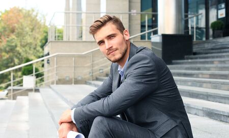 Handsome male business executive sitting on stairs outside a building.の写真素材