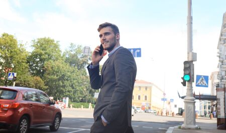 Young handsome businessman crossing the street using mobile phone.の写真素材