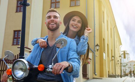 happy young couple riding scooter in town. Handsome guy and young woman travel. Adventure and vacations conceptの写真素材