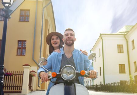 happy young couple riding scooter in town. Handsome guy and young woman travel. Adventure and...