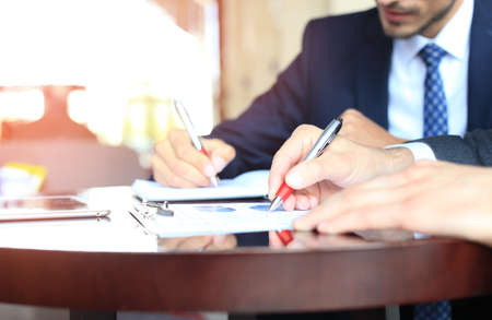 Two young businessmen analyzing financial document at meeting
