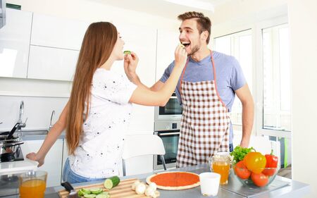Young couple making pizza in kitchen togetherの写真素材
