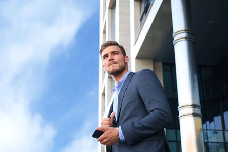 Young urban businessman professional on smartphone walking in street using mobile phone.の写真素材