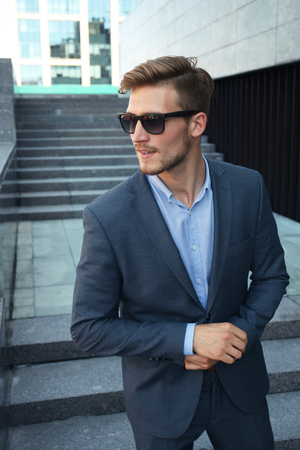 handsome stylish man in elegant suit and sunglasses in the street.の写真素材