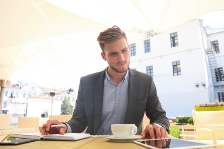 Businessman drinking coffee and reading news in cafe.の写真素材