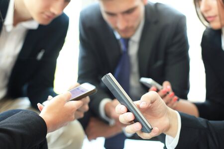 Group of people using smart phones sitting at the meeting, close up on hands.の写真素材