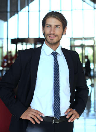 Portrait of happy young businessman standing in hotel lobby.の写真素材
