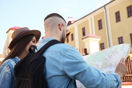 Happy couple walking outdoors sightseeing and holding a map.の写真素材