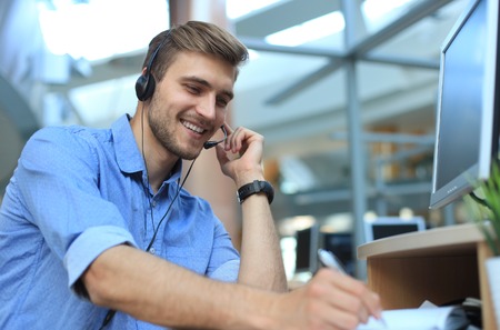 Smiling friendly handsome young male call centre operator.の写真素材