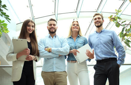 Young modern colleagues in smart casual wear looking at camera standing in the creative office.の写真素材