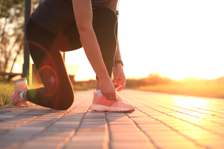 Young fitness attractive sporty girl runner ties up the shoelaces on her sports shoes getting ready to run.の写真素材