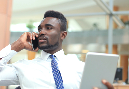 Successful african american entrepreneur using tablet computer and talking on phone.の写真素材
