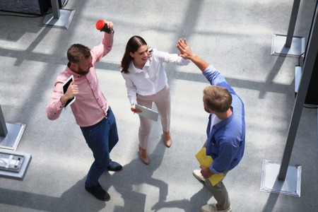 Top view of young modern colleagues in smart casual wear working together while spending time in the...