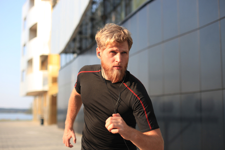 Fit athlete. Handsome adult man running outdoors to stay healthy, at sunset or sunrise. Runner.