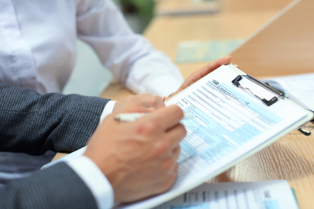 Man filling in U.S. Individual income tax return, tax 1040 at table.の写真素材