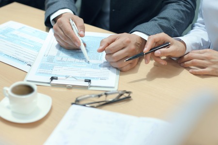 Man filling in U.S. Individual income tax return, tax 1040 at table.