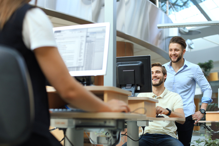 Group of young confident business people analyzing data using computer while spending time in the office.の写真素材