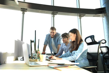 Young colleagues in smart casual wear working while spending time in the office.